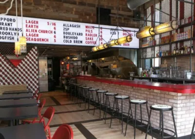 The interior of a restaurant with a bar and stools.