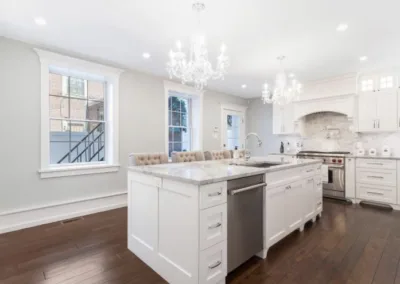 A white kitchen with hardwood floors and a chandelier.