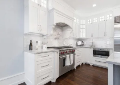 A white kitchen with stainless steel appliances and hardwood floors.