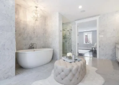 A white bathroom with marble floors and a tub.